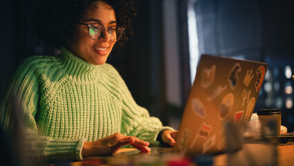 Fototapete - Positive Black Female Software Engineer Coding on Laptop Computer, Working with Inspiration in Her Studio. Woman Studying Late in the Evening. Modern Freelancer at Remote Work Concept.