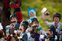 Assortment Of Clay Souvenirs. Souvenir Clay Figurines Of Men In National Moldovan Costumes With Jugs And Grapes In Their Hands. Moldavian Folk Art On Wine Day Theme. Selective Focus