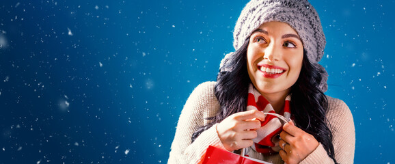 Wall Mural - Happy young woman holding a shopping bag in a snowy night