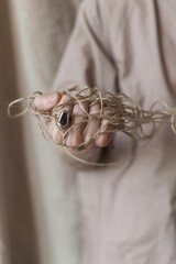 Wall Mural - Vertical closeup of a man's hand holding a fibers silk cotton linen jute rope