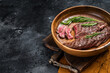 Fried sirloin flap or flank beef steak with herbs in a wooden plate. Black background. Top view. Copy space