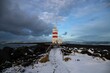 Snowy landscape with a lighthouse at the rocky coast