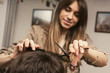 © velishchuk - Young man getting a modern haircut. Girl hairdresser cuts a guy with scissors. Men's fashion and style. Hair care, beauty industry, barber concept. Barber shop men hairstyle