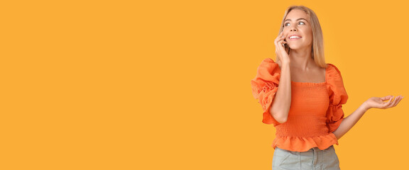 Wall Mural - Teenage girl talking by mobile phone on orange background with space for text