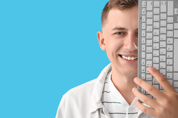 Sticker - Young man with computer keyboard on blue background, closeup