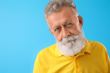 Wall Mural - Senior bearded man in yellow shirt on blue background