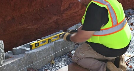 Wall Mural - Construction site worker installing newly constructed large block retaining wall construction near new home