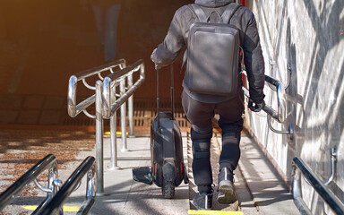 Man with unicycle on stairs. Obstacle for personal electric transport. Man carry on stairs carre unicycle. Barrier-free urban space, problems of transport infrastructure