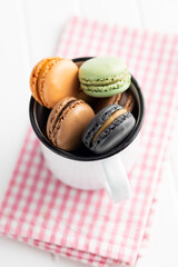 Wall Mural - Sweet macaron dessert. Colorful macarons in white mug.