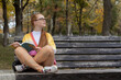 © Andrei - a beautiful girl with long red hair, wearing glasses, reading books in the park, in autumn, on a bench.