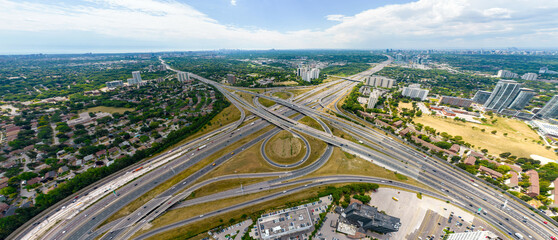 Top down aerial of cars drive across the expressway road in Canada. Cityscape and Highway. Transportation traffic at multilevel high speed road complex in North America.