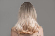 Blonde Woman With Transitional Ombre. Back View Hair. Grey Background