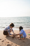 Asian cute little girl and her mother playing or making sand castle or digging with sand on tropical beach. Children with beautiful sea, sand blue sky. Happy kids on vacations seaside on the beach.