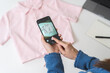 © KMPZZZ - Small SME business, asian young woman, girl hand using mobile phone taking photo of clothing for sell clothes on smartphone, stream selling online, show product present detail, entrepreneur e commerce