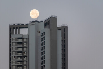 Wall Mural - A high rise skyscraper with a full moon in the sky above in the city of Mumbai.