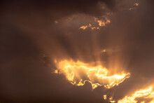 Rays Of Sunlight Beaming Through Dark Clouds In A Dramatic Sky.