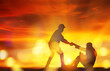 © ฺฺฺBoonterm - Silhouette engineer and male foreman pulling handshake, pulling the hand of a male worker who sits in despair, wanting to have a spirit of hope and stand up for success : Sunset background