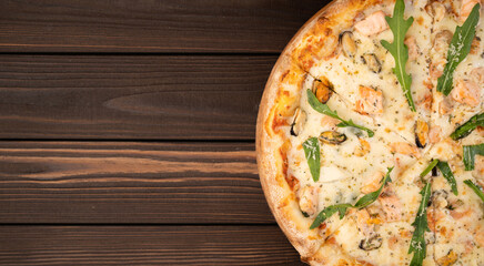 Gourmet seafood pizza on the wooden table with fresh scampi, mussels and clams.