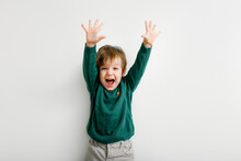 Cute Little Boy With Raised Hands Up With Happiness On White Wall Background