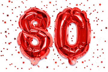 Wall Mural - The number of the balloon made of red foil, the number eighty on a white background with sequins. Birthday greeting card with inscription 80. Anniversary concept. Celebration event.