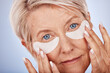 © M Einero/peopleimages.com - Skincare, portrait and senior woman with eyepads on face for anti aging facial on studio background. Beauty, cosmetics and mature lady with collagen mask or eye patches for wrinkles and eye wellness.