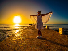 Woman Walking On Pier Near Sunny, Tropical Beach At Daybreak
