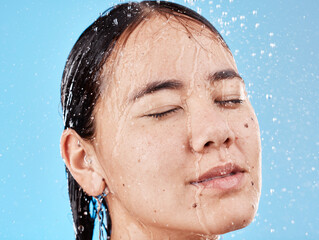 Wall Mural - Relax, water and face of a woman in the shower for cleaning, peace and health against a blue studio background. Skincare, wellness and Asian model with hair care, beauty and natural self care