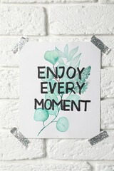 Wall Mural - Card with phrase Enjoy Every Moment attached on white brick wall
