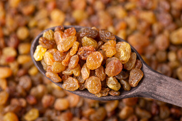 Poster - Macro shot of raisins in wooden spoon. Tasty sweet raisins background, adding raisins to pastry