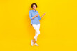 Leinwandbild Motiv Full length photo of positive pretty lady wear blue shirt pointing two fingers empty space isolated yellow color background