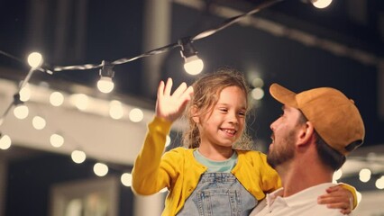 Wall Mural - Proud Handsome Father Helping His Little Beautiful Daughter to Change a Lightbulb in Fairy Lights Backyard Installation at Home. Father and Daughter High Five and Celebrate Successful Fix.