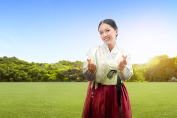 Wall Mural - Asian woman wearing a traditional Korean national costume, Hanbok, standing on the meadow field