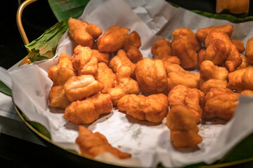 Wall Mural - Deep-fried traditional Thai dough or Pa Tong Ko in Thai language, deep-fried dough ready to serve, warm light from above.