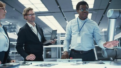 Aufkleber - African Industrial Robotics Engineer Discussing the Development of a Robotic Arm Machine with His Colleagues. Specialists with Laptop and Tablet Computers Research the Possibilities of the Robot.