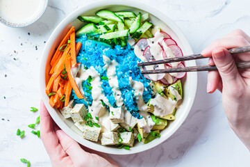 Wall Mural - Blue rice poke bowl with tofu, avocado, carrot, cucumber and radish. Healthy protein buddha bowl for vegetarian healthy diet.