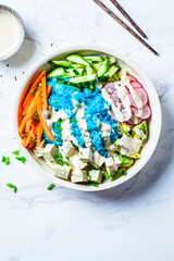 Wall Mural - Blue rice poke bowl with tofu, avocado, carrot, cucumber and radish. Healthy protein buddha bowl for vegetarian healthy diet.