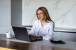 © dianagrytsku - Happy young woman using laptop in cook room