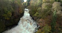 Slowly Reversing Drone Footage Of A Cascading Waterfall In A Gorge Surrounded By Colourful Trees In Autumn. Falls Of Clyde, Scotland.