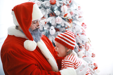 Wall Mural - Santa Claus sitting with little cute elves over Christmas background. Time of miracles. Gifts from Santa Claus.