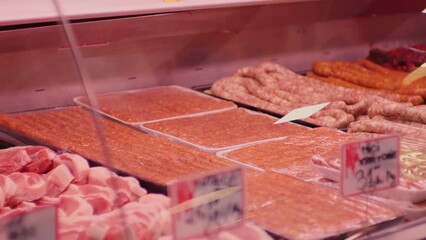 Wall Mural - Close up woman hands picking plastic container with miced meat from shop window. Butchery worker serving customers.