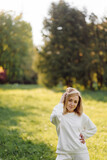 Fototapeta Przestrzenne - Young blonde girl is wearing a white hoodie smiling and walking in the woods
