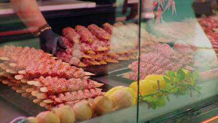 Wall Mural - Male hands replacing turkish kebab in the fridge showcase in butchers shop. Butchery worker fulfilling the gaps with precessed meat.