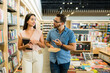 © AntonioDiaz - Smiling couple talking about books while buying novels at the shop