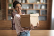 © Prostock-studio - Happy young woman holding box parcel and smiling