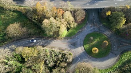 Wall Mural - Slow aerial view of traffic using a small roundabout in the fall