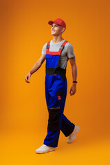 Wall Mural - Full length shot of a young male worker in uniform on yellow background