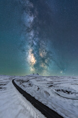 Long asphalt road surrounded with snow and ice at night in Iceland