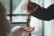 © kamiphotos - A home rental company employee is handing the house keys to a customer who has agreed to sign a rental contract, explaining the details and terms of the rental. Home and real estate rental ideas.
