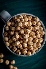 Wall Mural - Roasted spicy chickpeas. Roasted chickpeas in a porcelain cup on wooden white background