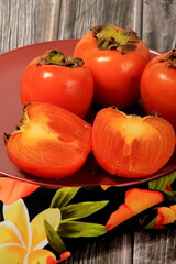 Fresh persimmon fruit on plate. Persimmon fruit Old board background